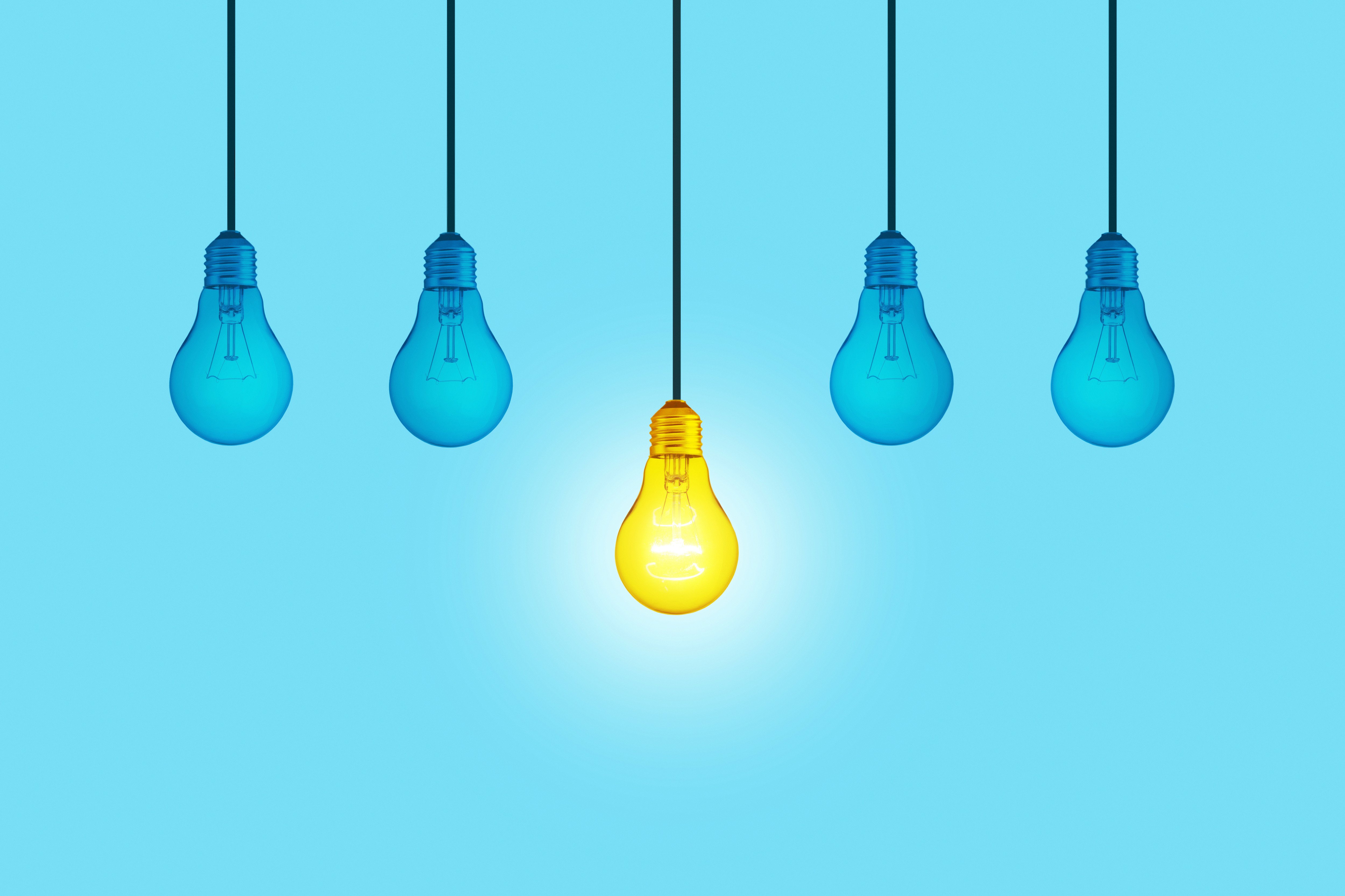 blue background image with four blue light bulbs hanging down and in the middle a yellow lit up light bulb hangs down