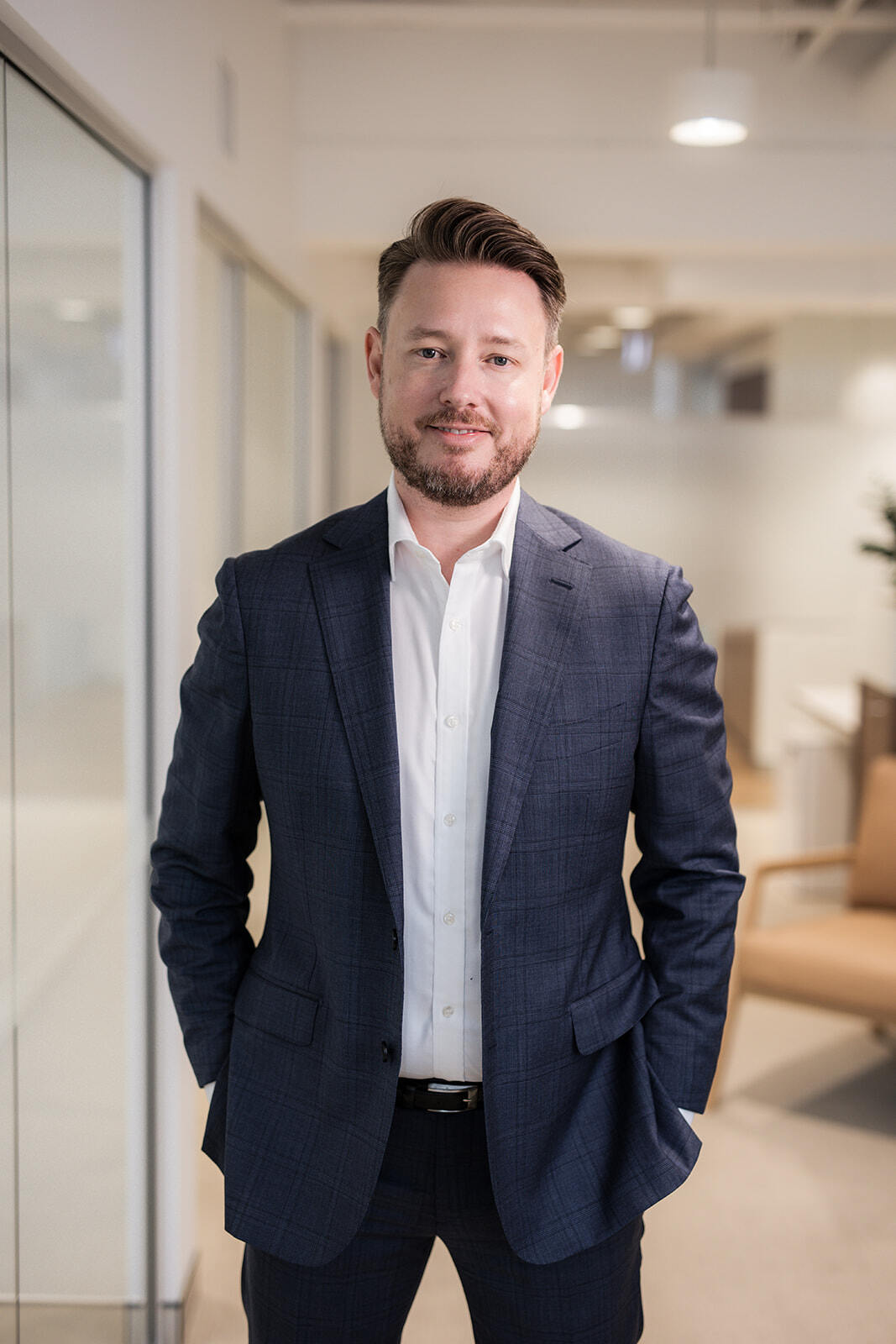 Chris standing and staring into camera blurred office background slight smile